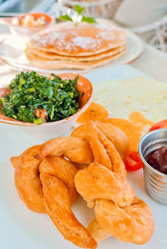 Golden fried chicken strips with a spinach side, maple syrup-dipped pancakes in the background, and a dollop of honey mustard on the side, deliciously plated.