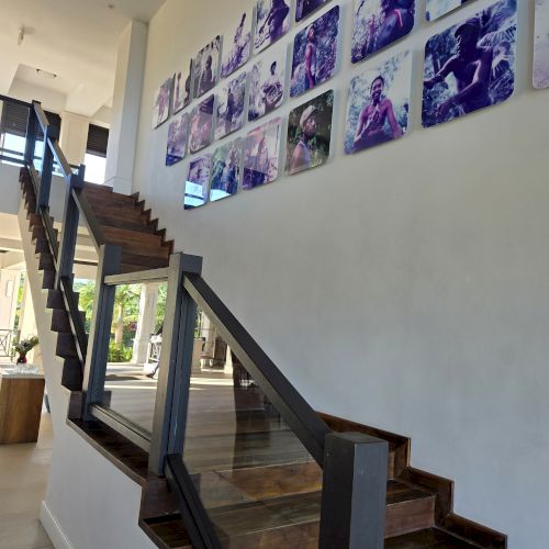 A modern staircase with dark wooden steps and railings, gallery-style photos on the wall, bright natural light, open space, minimalist decor.