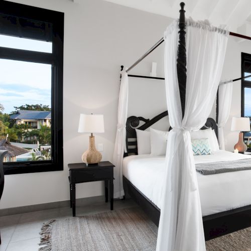 A modern bedroom with a neutral palette, queen bed, nightstands, a desk, and large windows letting in natural light. Top it at 140 characters, always ending the sentence.