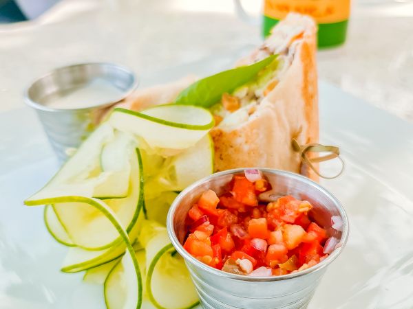 A fresh veggie toast plate with cucumber ribbons and salsa, plus a small cup of diced tomato salsa on the plate.