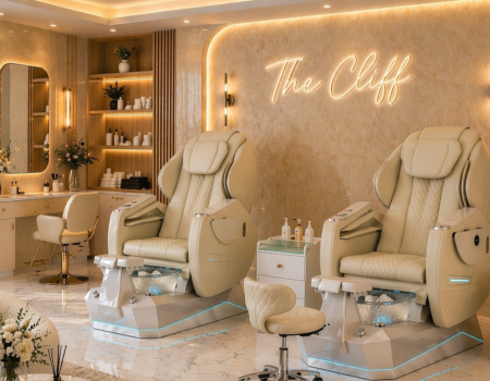 A luxe beauty spa with cream pedicure chairs, soft lighting, marble floors, and a glowing sign &ldquo;The Cliff&rdquo; for a serene pampering experience.